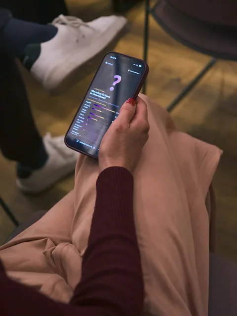 Ein Gast stimmt auf dem Smartphone ab, die Frage der Live-Umfrage ist auf dem Bildschirm zu sehen