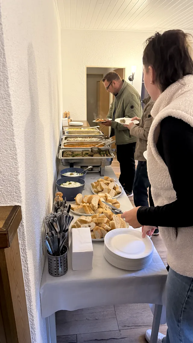 Buffet im See-Idyll — Gäste nehmen sich Brot und warme Speisen